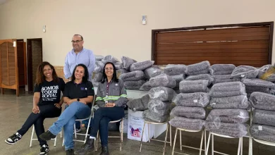 Pessoas posando ao lado de cobertores a serem doados a famílias em estado de vulnerabilidade