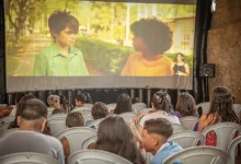 Plateia formada por crianças e adolescentes acompanha a exibição de um curta-metragem, em telão montado em espaço cultural de Mangaratiba.