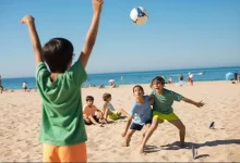Crianças jogando futebol de areia na praia