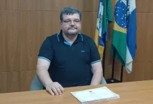 TSE vai decidir destino de Rubão: Na foto, rubão está sentado à mesa com diploma sobre ela. ao fundo, bandeiras da cidade, do estado e do país