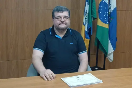 TSE vai decidir destino de Rubão: Na foto, rubão está sentado à mesa com diploma sobre ela. ao fundo, bandeiras da cidade, do estado e do país