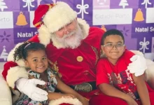 Papai Noel abraçando duas crianças