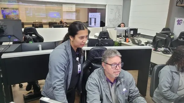Jovem observando colega de trabalho teclando o computador
