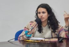 Historiadora à mesa fazendo uma palestra