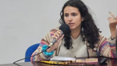 Historiadora à mesa fazendo uma palestra