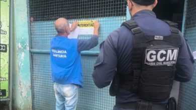 Agente da prefeitura afixando documento de interdição