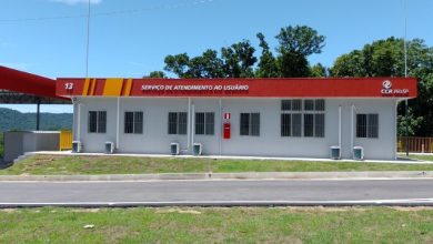 Base 13 da CCR RioSP na rodovia Rio-Santos, com fachada branca e marquise vermelha identificada como Serviço de Atendimento ao Usuário, em área cercada por vegetação em operação especial para o carnaval.