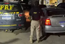 Agente da PRF entre o veículo apreendido e a viatura