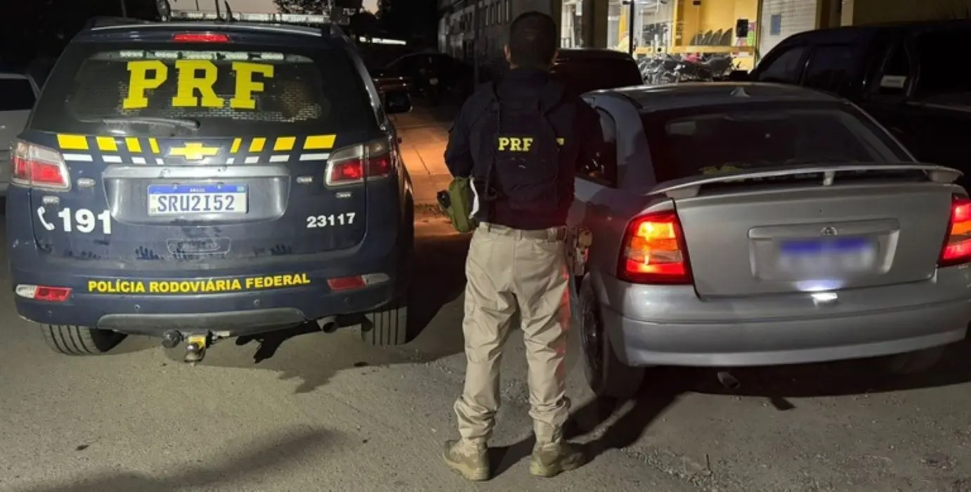 Agente da PRF entre o veículo apreendido e a viatura