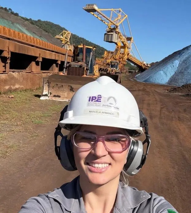 Colaboradora do Porto Sudeste posando para foto em frente a uma grande máquina