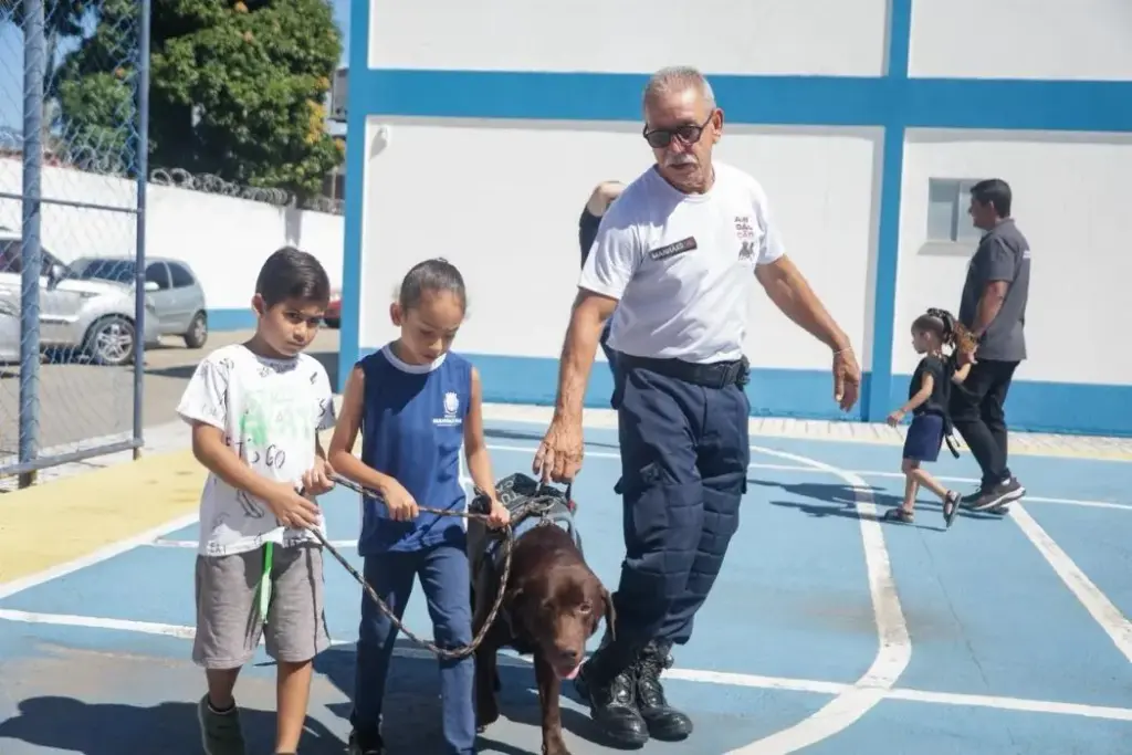 Crianças participam de atividade com cão do projeto, acompanhadas por agente do GAC