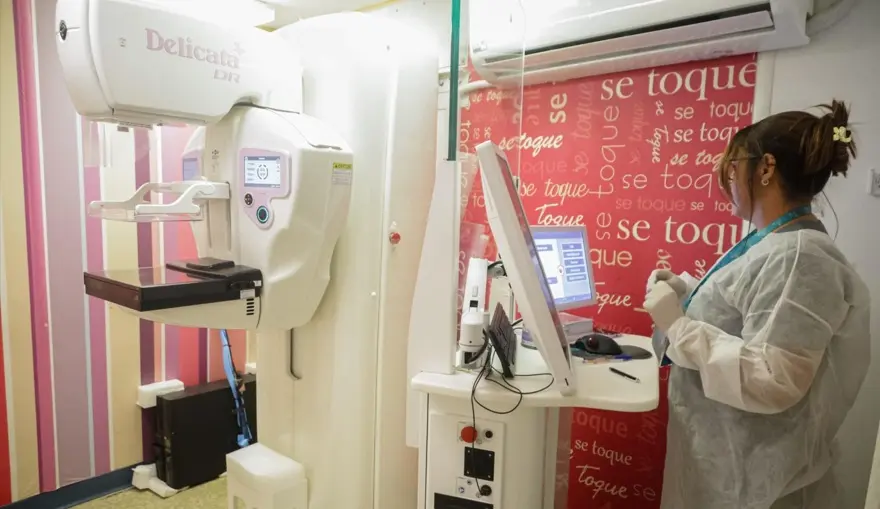 Profissional de saúde realiza preparação de equipamento de mamografia dentro da unidade móvel