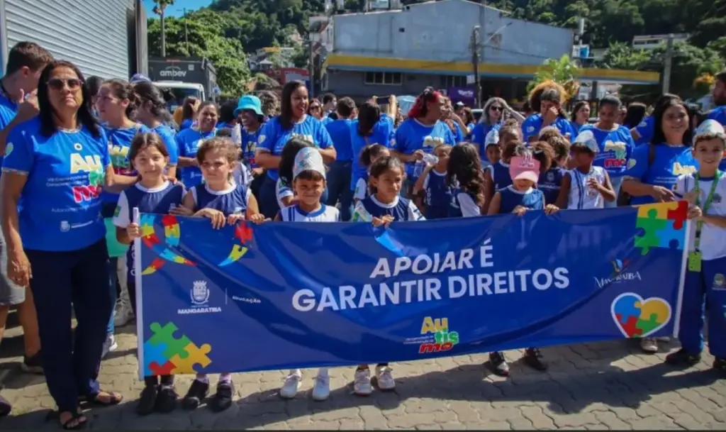 Crianças, educadores e famílias participam da caminhada com faixa