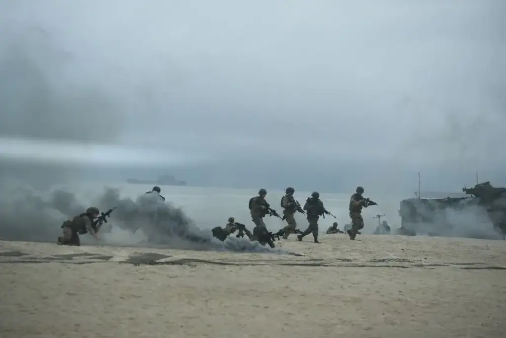 Militares do Brasil e da França avançam armados após desembarque na praia
