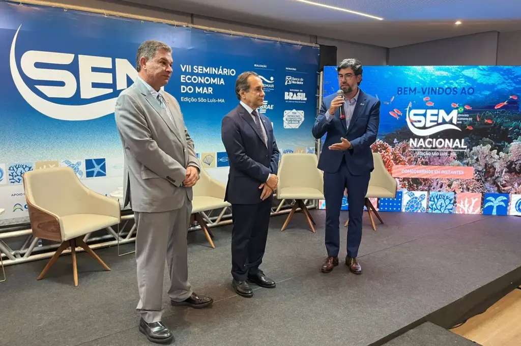 Três homens no palco para discursarem