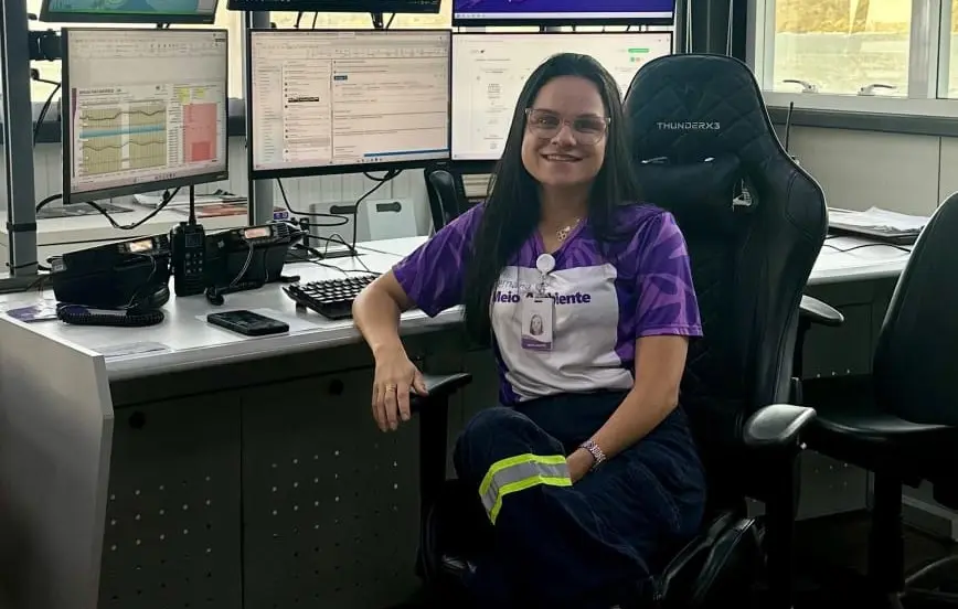 Colaboradora do Porto Sudeste posa para foto sentada à mesa