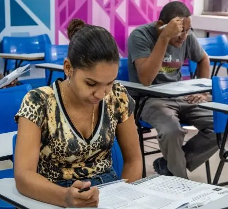 Dois alunos fazendo prova numa sala de aula