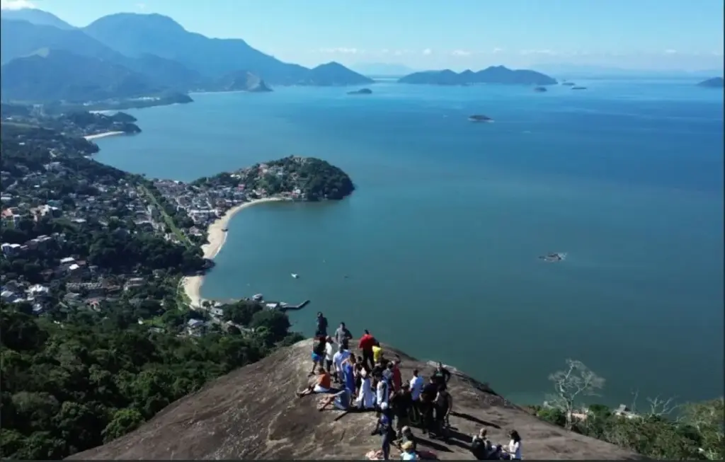 Do alto da Pedra do Urubu, visitantes contemplam uma das vistas mais impressionantes da Costa Verde, com panorama