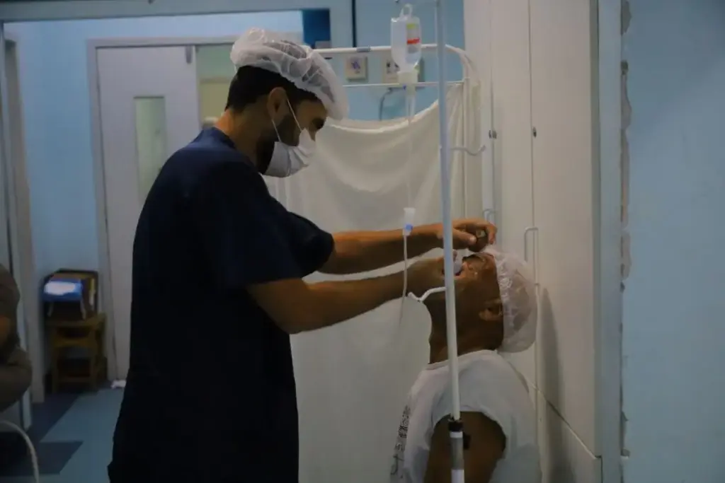Médico aplica colírio no paciente