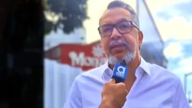 Marcio Canella está falando ao microfone identificado com a logo marca do jornal atual.