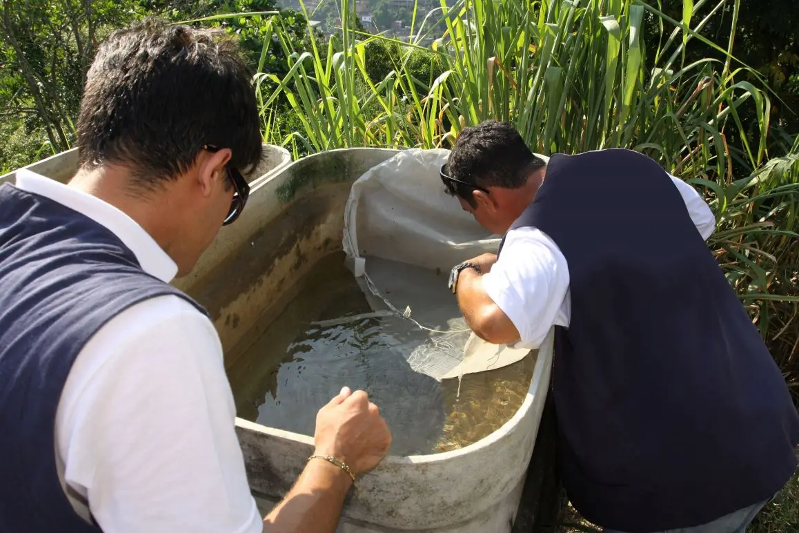 Dois homens olhando uma caixa d'água