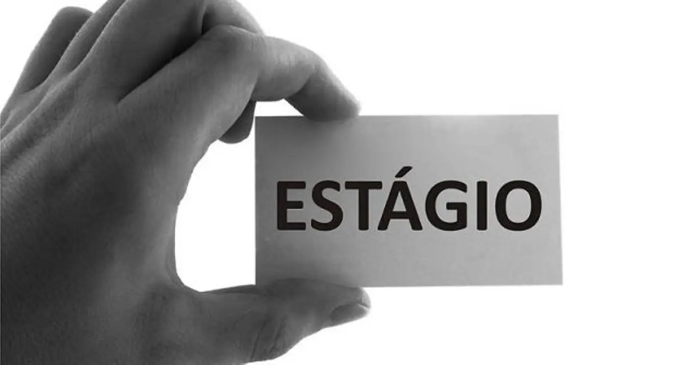 Mão segunrando placa em que está escrito a palavra estágio