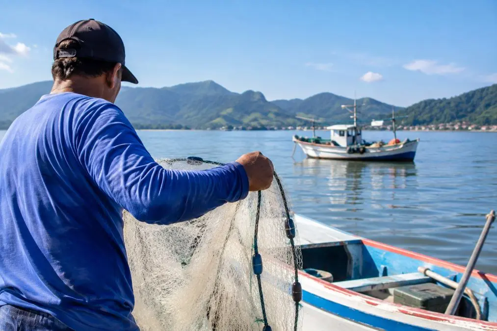 Pescador artesanal realiza atividade de pesca em embarcação