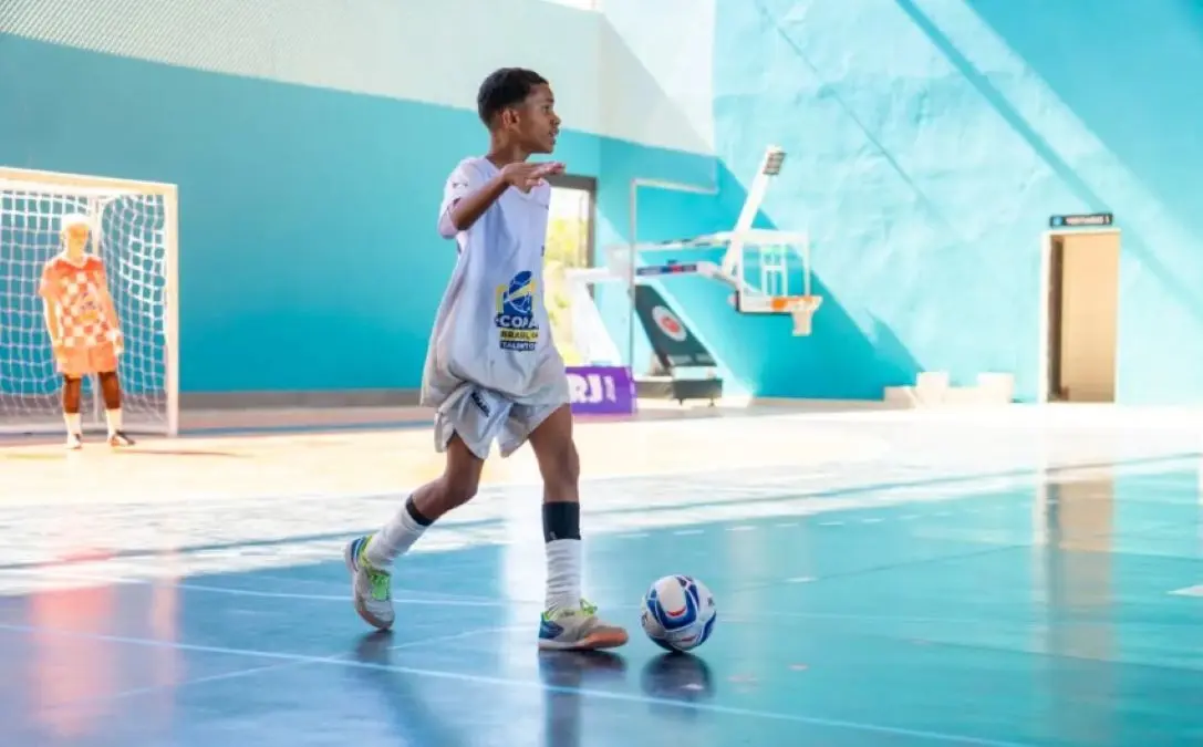 Estudante conduz a bola na partida de futsal