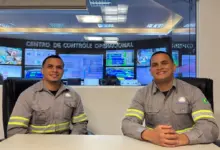 Dois irmãos gêmeos sentados à mesa sorrindo