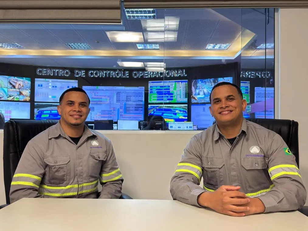 Dois irmãos gêmeos sentados à mesa sorrindo