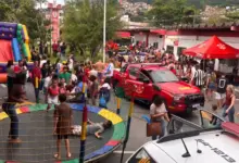 Crianças brincam em cama elástica e brinquedo inflável, enquanto famílias visitam o quartel do 10º GBM, com viaturas dos bombeiros em exposição.