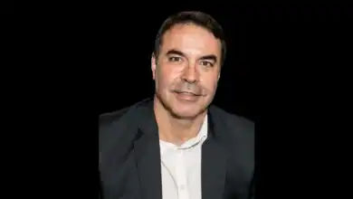 Retrato de Renato Regazzi, colunista do Jornal Atual e participante do livro Economia Azul e Cidades, usando paletó escuro e camisa branca sobre fundo preto.